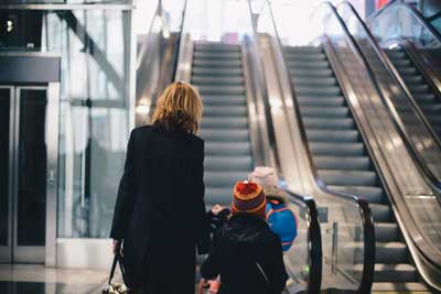 En kvinna och ett barn står vid foten av en rulltrappa.